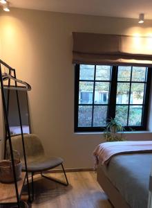 ein Schlafzimmer mit einem Bett, einem Stuhl und einem Fenster in der Unterkunft Vakantiehoeve 'De Zandrug' in Stekene