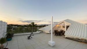 d'un balcon avec un toit blanc, une table et des chaises. dans l'établissement Roof top dans les quartiers sud de Nouméa, à Nouméa