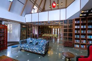 eine Bibliothek mit Sofa und Bücherregalen in der Unterkunft The Preserve Stone House Bungalow in Meppādi