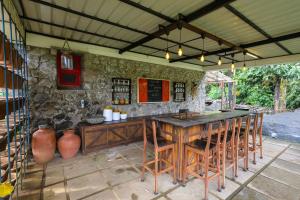 una cocina al aire libre con una gran mesa de madera y taburetes en The Preserve Stone House Bungalow, en Meppādi