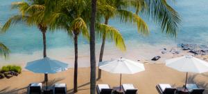 a beach with palm trees and chairs and umbrellas at 5-Star Boutique Hotel The Lombok Lodge in Tanjung