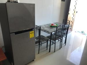 a kitchen with a table with chairs and a refrigerator at Mikhai Guest House near Las Cazas de Acuzar in Bagac