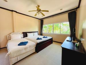 a bedroom with two beds and a ceiling fan at Baan Faa Talaychan Resort in Chao Lao Beach