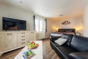 a living room with a black leather couch and a bed at Fünf Harzer Berge Oderberg in Sankt Andreasberg