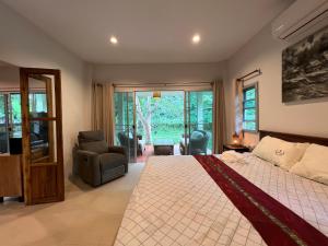 a bedroom with a large bed and a chair at Creek Cottage Chaeson in Ban Mun Thung