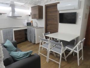 a kitchen and a living room with a table and chairs at Alojamiento Rural Cueva del Cerro in Casas del Cerro