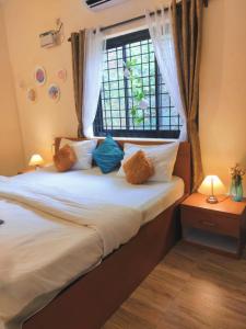 a bedroom with a bed with pillows and a window at 2bhk Bunglow with terrace- Candolim in Candolim