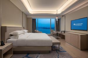a bedroom with a bed and a flat screen tv at Wyndham Shaoxing Keqiao in Shaoxing