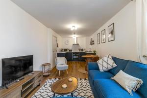 un soggiorno con divano blu e TV di Central 1BD with Free Underground Parking! a Cheltenham