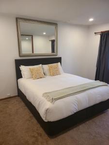 a bedroom with a large bed with a mirror on the wall at Te Papatapu Retreat in Raglan +14 photos