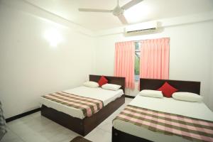 a bedroom with two beds and a window at Pleasure Island Holiday Home in Dambulla