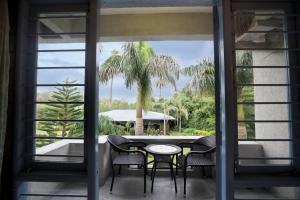 a balcony with a table and chairs and a palm tree at Hummingbird Resort in Mount Ābu