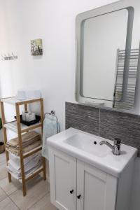 La salle de bains est pourvue d'un lavabo blanc et d'un miroir. dans l'établissement doolinyoga luxury accommodation, à Doolin