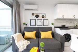 sala de estar con sofá gris y almohadas amarillas en THE WHITE CORNER BY HOMESTAYGRANCANARIA en San Bartolomé