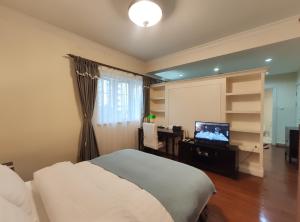 上海的住宿－國際麗都公館，一间卧室配有一张床和一张书桌及电视