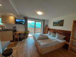 a bedroom with a bed and a kitchen with a window at Bio & Reiterhof der Veitenhof - Pferde, Berge, Wellness & Freiheit im Ötztal in Niederthai