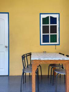 una mesa y sillas contra una pared amarilla con una ventana en The kn kohlarn resort en Ko Larn