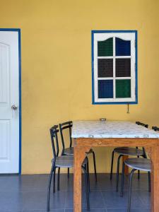 uma mesa e cadeiras contra uma parede amarela com uma janela em The kn kohlarn resort em Ko Larn