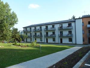 ein großes weißes Gebäude mit Balkon und Rasen in der Unterkunft Harmonie Apartment in Lipno nad Vltavou