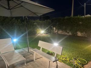 un banco y una silla bajo una sombrilla por la noche en Villa Aurora e Villa Oceano, en Fontane Bianche