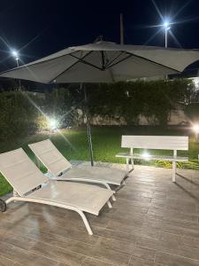 2 sillones, sombrilla y mesa de picnic en Villa Aurora e Villa Oceano, en Fontane Bianche