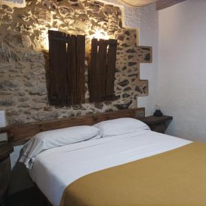 um quarto com uma cama e uma parede de pedra em O Viraventos em Betanzos