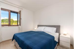 a white bedroom with a blue bed and a window at Villa Monti by Briskva in Cerovlje +37 photos
