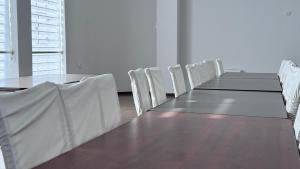 a conference room with a long table and white chairs at Parvoz Hotel in Urganch