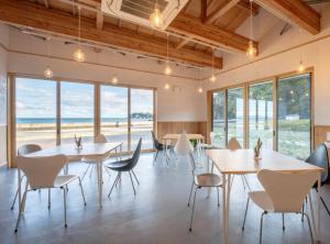 a restaurant with tables and chairs and a view of the ocean at RISE BEACH Okumatsushima in Higashimatsushima