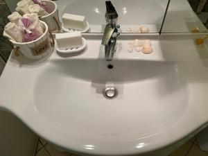 a white sink with a faucet and some soap at CHARMING APARTMENT WITH THE PRIVATE GARDEN in Orsay