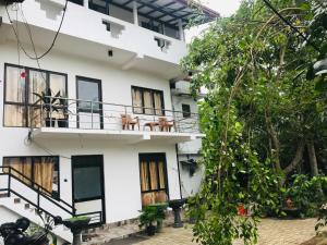 a white building with windows and a balcony at Meyola Guest house in Weligama