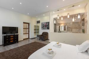 Un dormitorio con una gran cama blanca y un televisor. en Domeniul Burzenland, en Heldsdorf