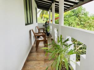 a corridor of a house with two chairs and plants at Meyola Guest house in Weligama