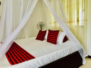 a bedroom with a bed with red and white pillows at Meyola Guest house in Weligama