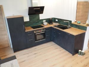 een keuken met zwarte kasten en een spoelbak bij Ferienwohnung Sonnenseite in Cochem