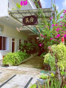 un bâtiment avec un panneau et quelques plantes et fleurs dans l'établissement Flower Home ផ្ទះសំណាក់ ហូមផ្កា, à Sihanoukville