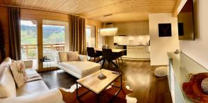 Chalet CARVE - Apartments EIGER, MOENCH and JUNGFRAU في جريندلفالد: غرفة معيشة مع أريكة وطاولة