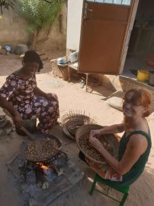 two women are cooking over an open fire at Live with the locals in Bamboo House in Tanji