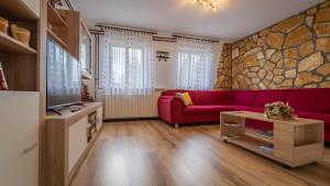 - un salon avec un canapé rouge et un mur en pierre dans l'établissement Apartman Ornela, à Delnice