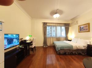 a hotel room with a bed and a television at Ladoll Service Apartments in Shanghai