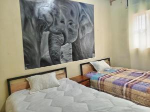 a bedroom with two beds and a picture of an elephant at Akagera guide's House in Kabarondo