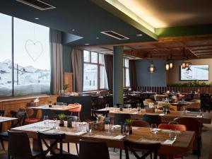 ein Restaurant mit Tischen und Stühlen mit einem Herz am Fenster in der Unterkunft OBERTAUERN PLACESHOTEL by Valamar in Obertauern