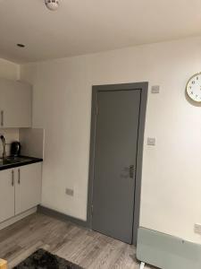 an empty room with a door and a clock on the wall at Modern studio flat in Romford in Havering atte Bower