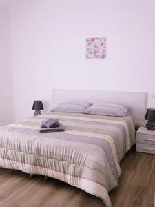 a white bedroom with a large bed with two lamps at Da Nonna Maria in Grottaglie
