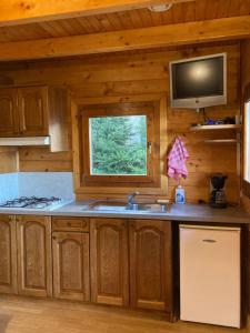 a kitchen with a sink and a window in a cabin at Camping-Chalets La Favière in Lac des Rouges Truites