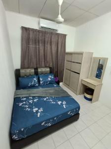 a bedroom with a blue bed with flowers on it at Adempuri Homestay 3 in Jitra