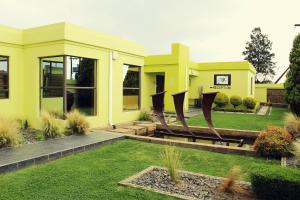una casa amarilla con césped delante en El DiVino Guesthouse, en Newcastle