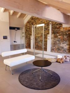 a white bench and table in a room with a stone wall at Hotel Aracoeli in Orta San Giulio