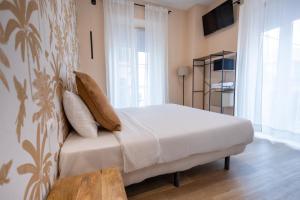 1 dormitorio con 1 cama con sábanas y almohadas blancas en The Clover, en Sevilla