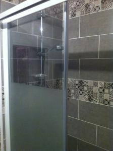 La salle de bains est pourvue d'une douche avec une porte en verre. dans l'établissement La Pause Bien-être face Pyrénées, à Livron